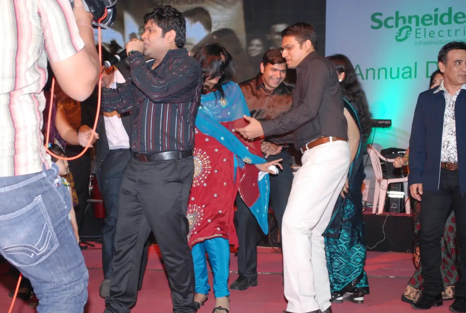 Man and woman speaking on stage at night with blue lighting